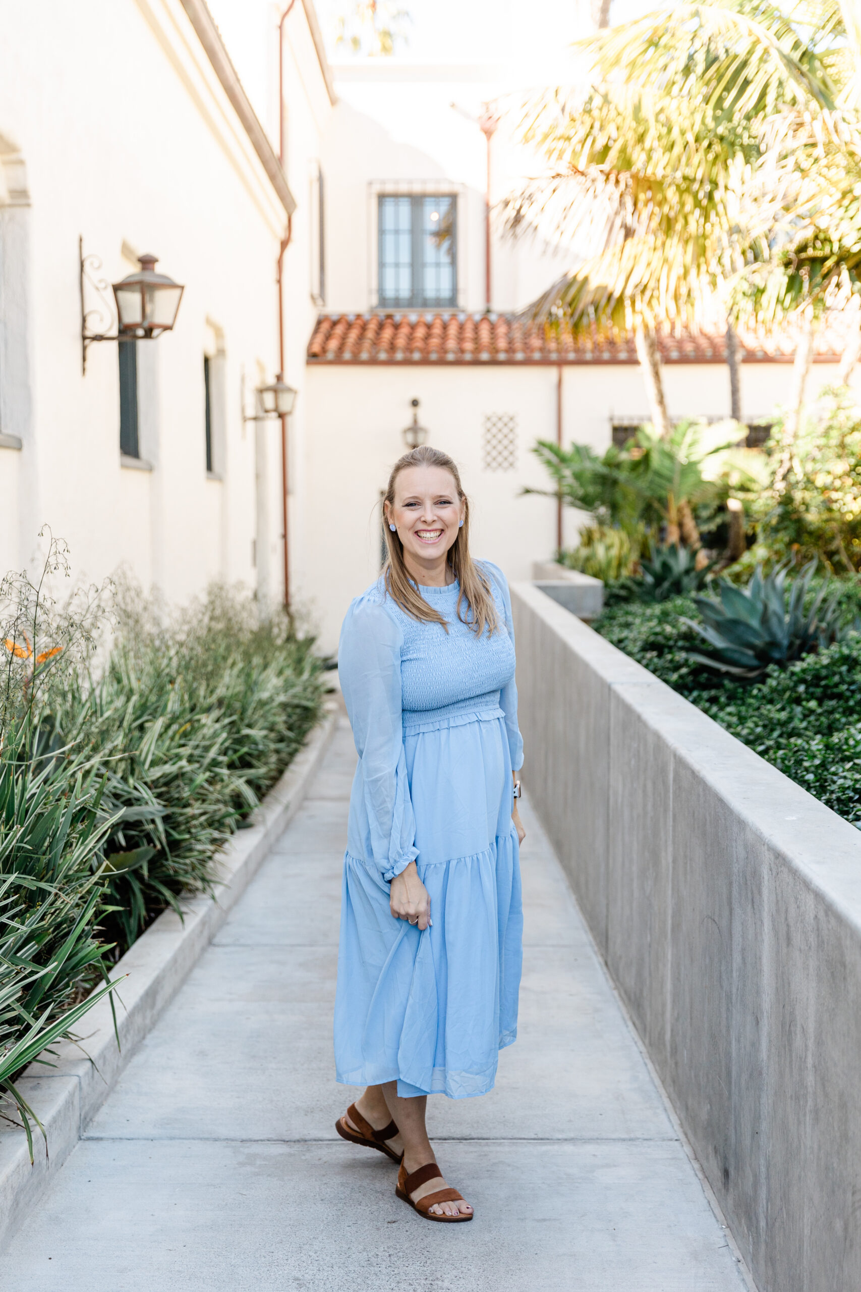 Ashley owner of Heirlooms and Lace Studios in a blue dress outside a wedding venue in Santa Barbara California