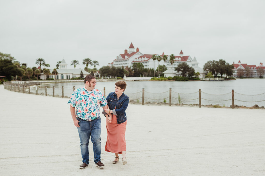 A couple walks on the beach between the Disney's Grand Floridian Resort and the Disney's Polynesian Resort. 